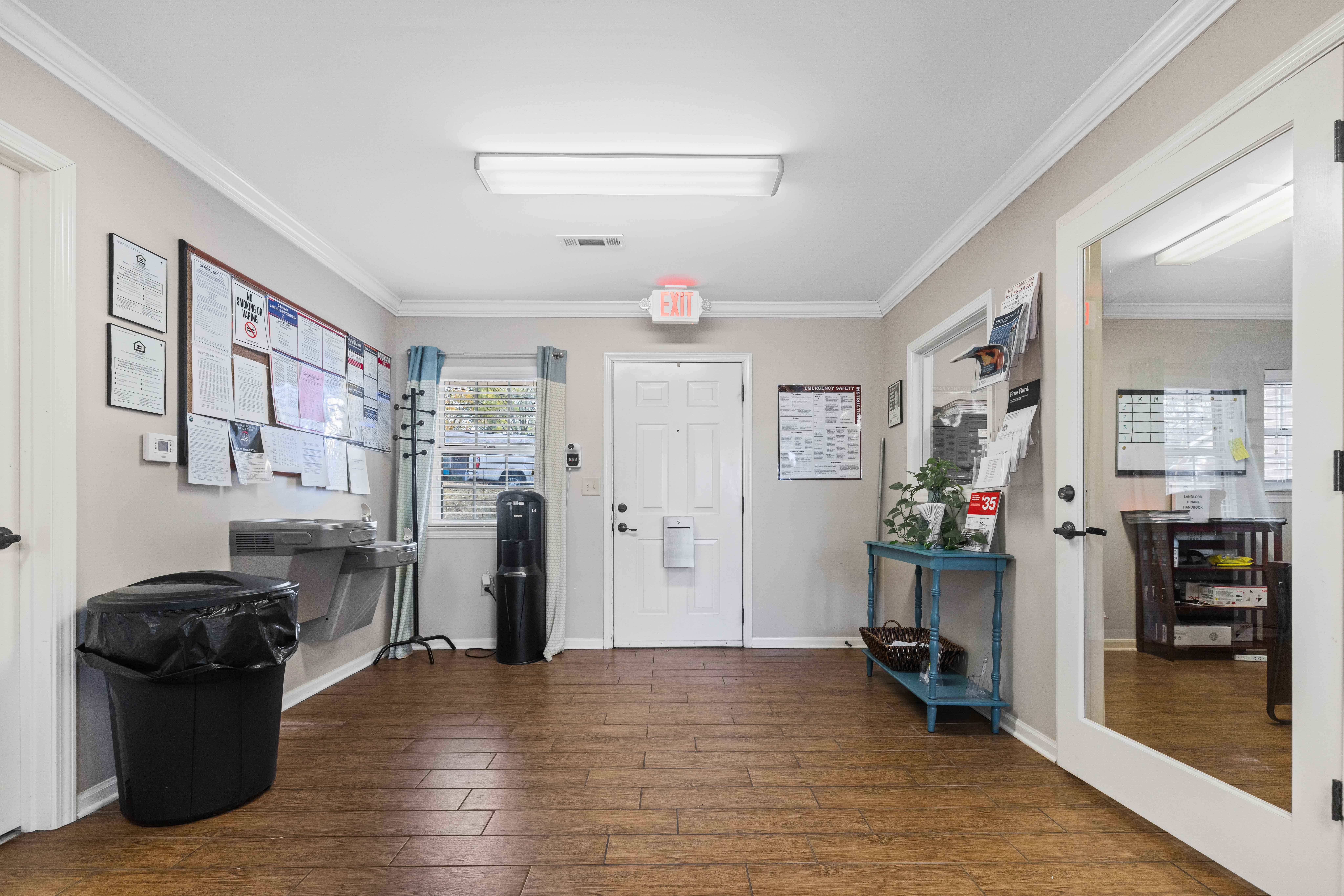 A hallway with a white door and a bulletin board on the wall.